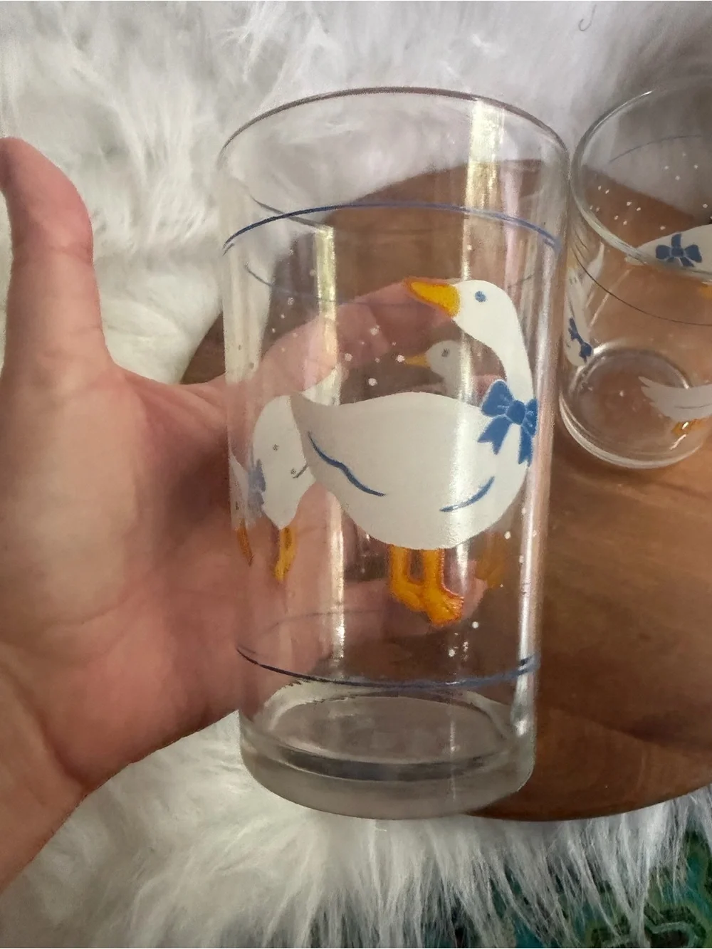 A pair of vintage clear glass tumblers with white geese and blue bows.